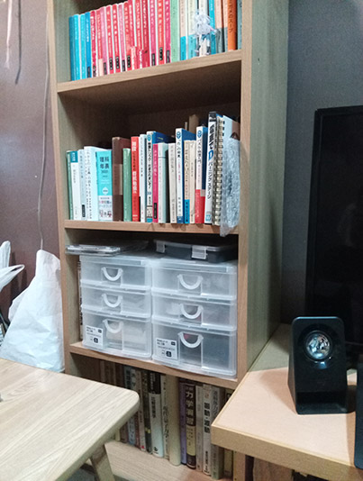 本棚の写真。1・2段目に文庫本、3段目に道具箱、4段目に教科書。
